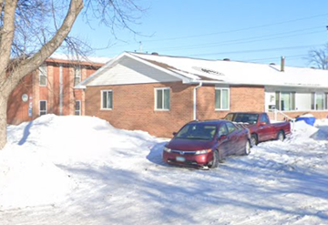 Fargo house for rent - A red car is parked in front of a brick building with snow on the ground.