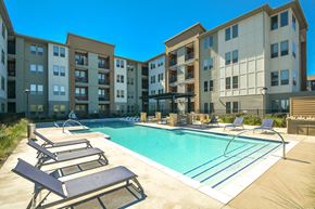 San Antonio apartment for rent - A swimming pool surrounded by sun loungers in front of apartment buildings.