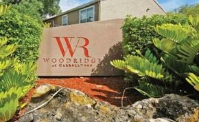 Tampa apartment for rent - A sign for Woodridge at Garrasbill stands in front of a building.