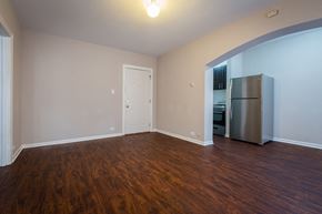 Chicago apartment for rent - an empty living room with wood flooring and a refrigerator