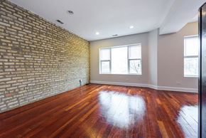 Chicago apartment for rent - an empty living room with a brick wall and wood floors