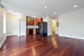 Chicago apartment for rent - an empty living room with a kitchen with a refrigerator