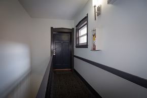 Chicago apartment for rent - a hallway with white walls and a black door and a window