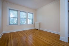 Chicago apartment for rent - a living room with wood floors and a radiator and three windows
