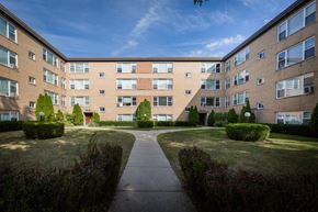 Chicago apartment for rent - exterior view of a brick apartment building with sidewalks and grass