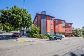 Oakland apartment for rent - A street view of a red building with cars parked in front.
