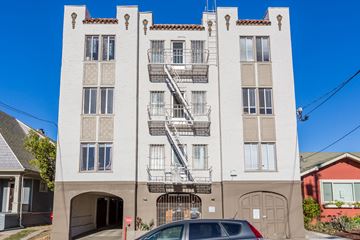 Oakland apartment for rent - A white building with a red roof and a car parked in front.