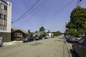 Oakland apartment for rent - A street with cars parked on both sides and houses in the background.