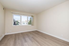 Oakland apartment for rent - Empty room with a window and wooden flooring.