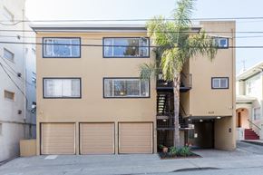 Oakland apartment for rent - A tan building with a palm tree in front.