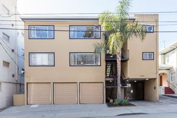 Oakland apartment for rent - A tan building with a palm tree in front.