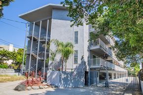 Oakland apartment for rent - A white building with balconies and a gate in front.