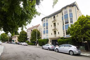 Oakland apartment for rent - A street with cars parked on the side and apartment buildings in the background.