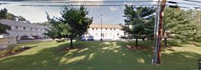 Lakewood apartment for rent - A grassy area with trees and a building in the background.