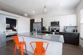 Dallas apartment for rent - a kitchen with an island with orange chairs and a counter top