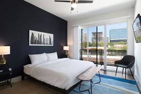 Dallas apartment for rent - a bedroom with a white bed and a black wall and a balcony