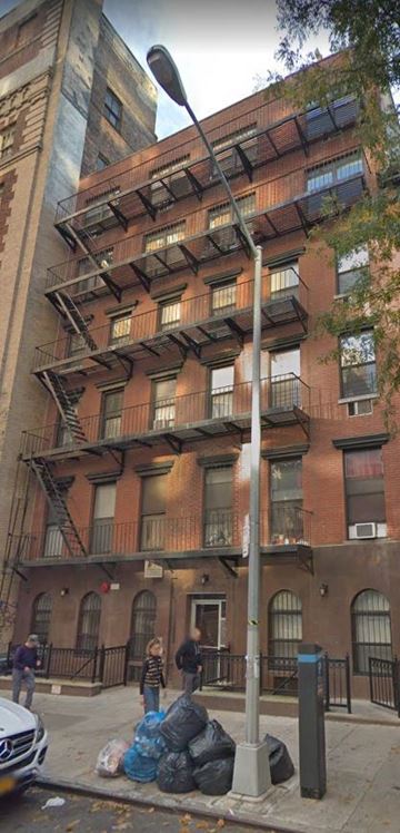 New York apartment for rent - a tall building with a lot of garbage on the street