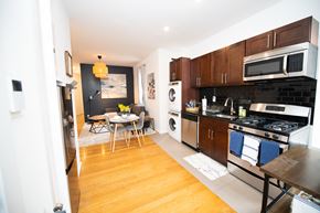 New York apartment for rent - a kitchen with wooden cabinets and appliances and a dining room with a table and chairs