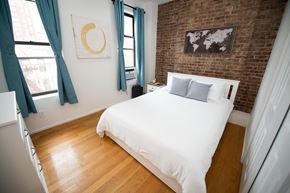 New York apartment for rent - a bedroom with a bed and a brick wall and blue curtains