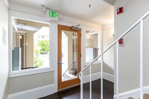 San Francisco apartment for rent - A hallway with a white railing and a green exit sign.