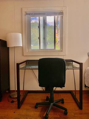 Ithaca apartment for rent - A black chair sits in front of a desk with a lamp and a window in the background.