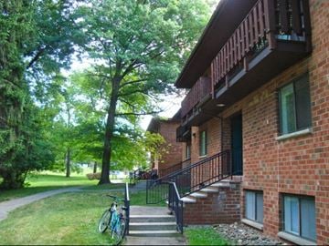 Ithaca apartment for rent - a brick building with stairs and a bike parked outside