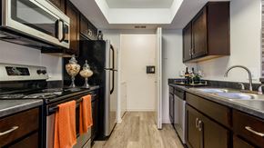 Stow apartment for rent - a kitchen with black appliances and wooden cabinets and a sink