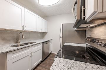 Cincinnati apartment for rent - A kitchen with white cabinets and a black stove top oven.
