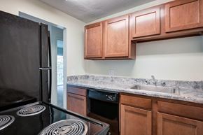 Cincinnati apartment for rent - A kitchen with a black refrigerator and brown cabinets.