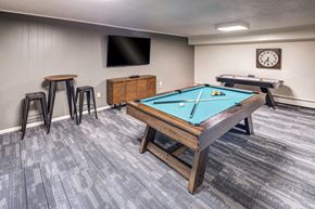 Oakwood Village apartment for rent - A room with a pool table, a TV, a clock, and a bar stool.
