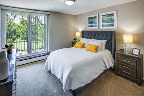 Oakwood Village apartment for rent - A bedroom with a large bed and a window overlooking a green area.