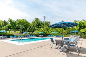 Pittsburgh apartment for rent - a swimming pool with blue umbrellas and chairs next to it