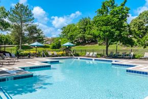 Pittsburgh apartment for rent - a swimming pool with chairs and umbrellas in a yard with trees
