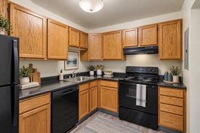 Pittsburgh apartment for rent - A kitchen with wooden cabinets and black appliances.