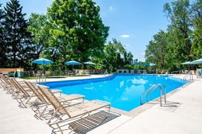 Pittsburgh apartment for rent - a swimming pool with wooden chairs and umbrellas