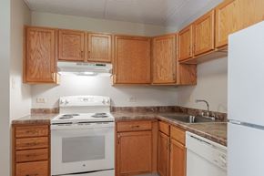 Pittsburgh apartment for rent - an empty kitchen with white appliances and wooden cabinets