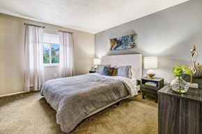 South Park apartment for rent - A bedroom with a large bed and a nightstand with a vase of flowers on it.