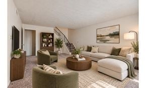 Rochester townhouse for rent - A living room with a white couch, green armchairs, and a rug.