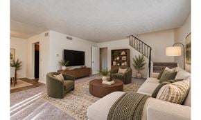 Rochester townhouse for rent - A living room with a white couch, a green armchair, and a coffee table.