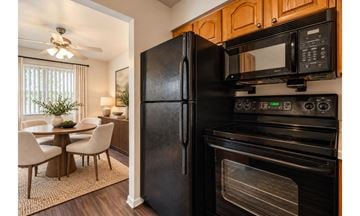 Rochester townhouse for rent - A black fridge and microwave in a kitchen with wooden cabinets.