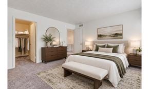 Rochester townhouse for rent - A bedroom with a large bed and a bench in front of it.