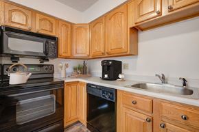 Rochester townhouse for rent - a kitchen with black appliances and wooden cabinets