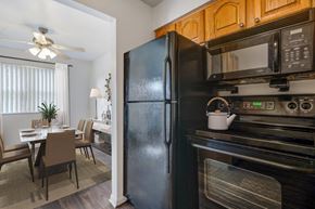 Rochester townhouse for rent - a kitchen with a black refrigerator and microwave and a dining room table