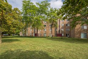 Guilderland Center apartment for rent - A grassy area in front of a brick building with trees on the left.