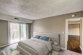 Guilderland Center apartment for rent - A bedroom with a large bed and a sliding glass door.
