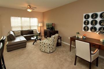 Watertown apartment for rent - A living room with a fan, a couch, a chair, and a cabinet with a television on top.