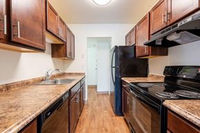 Syracuse apartment for rent - a kitchen with wooden cabinets and black appliances