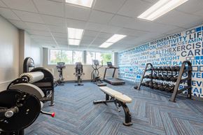 Syracuse apartment for rent - a gym with weights and other exercise equipment in a room with a wall of writing