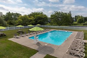 Syracuse apartment for rent - a resort style pool with lounge chairs and a green umbrella