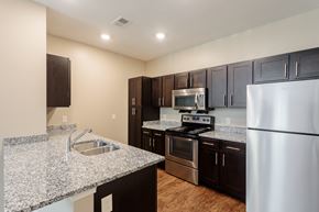 Camillus apartment for rent - kitchen with espresso cabinets, stainless appliances, and laminate plank floors
